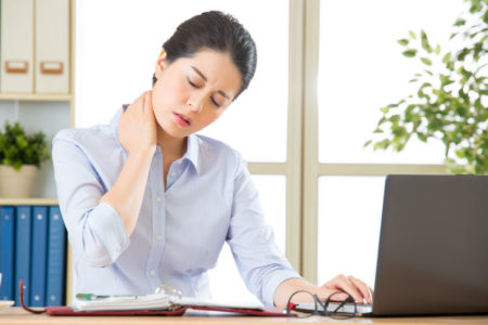 business woman at desk holding neck in pain