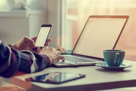 Man working on notebook, with a fresh cup of tea or coffee. Home work concept