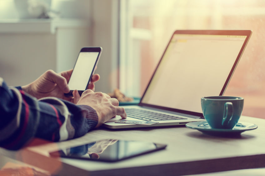 Man working on notebook, with a fresh cup of tea or coffee. Home work concept